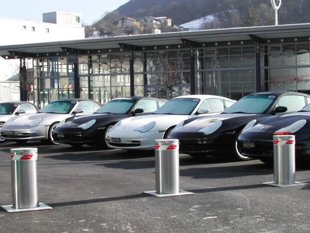 Op de foto zie je meerdere pillars en bollard. Deze komen uit de grond en zorgen voor terreinbeveiliging. Achter de pillards staan een aantal dure auto's.